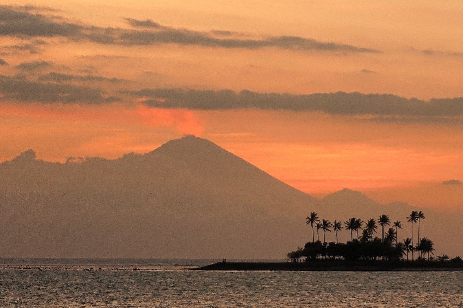 Bali's Mount Agung volcano silhouetted across the Lombok Strait from Senggigi Beach at dusk