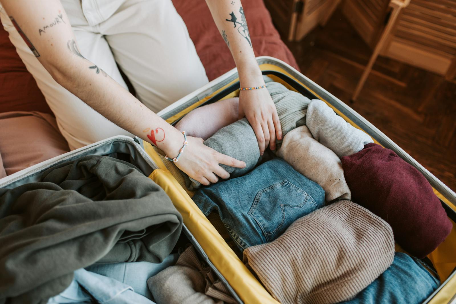 Person packing folded clothes into a suitcase