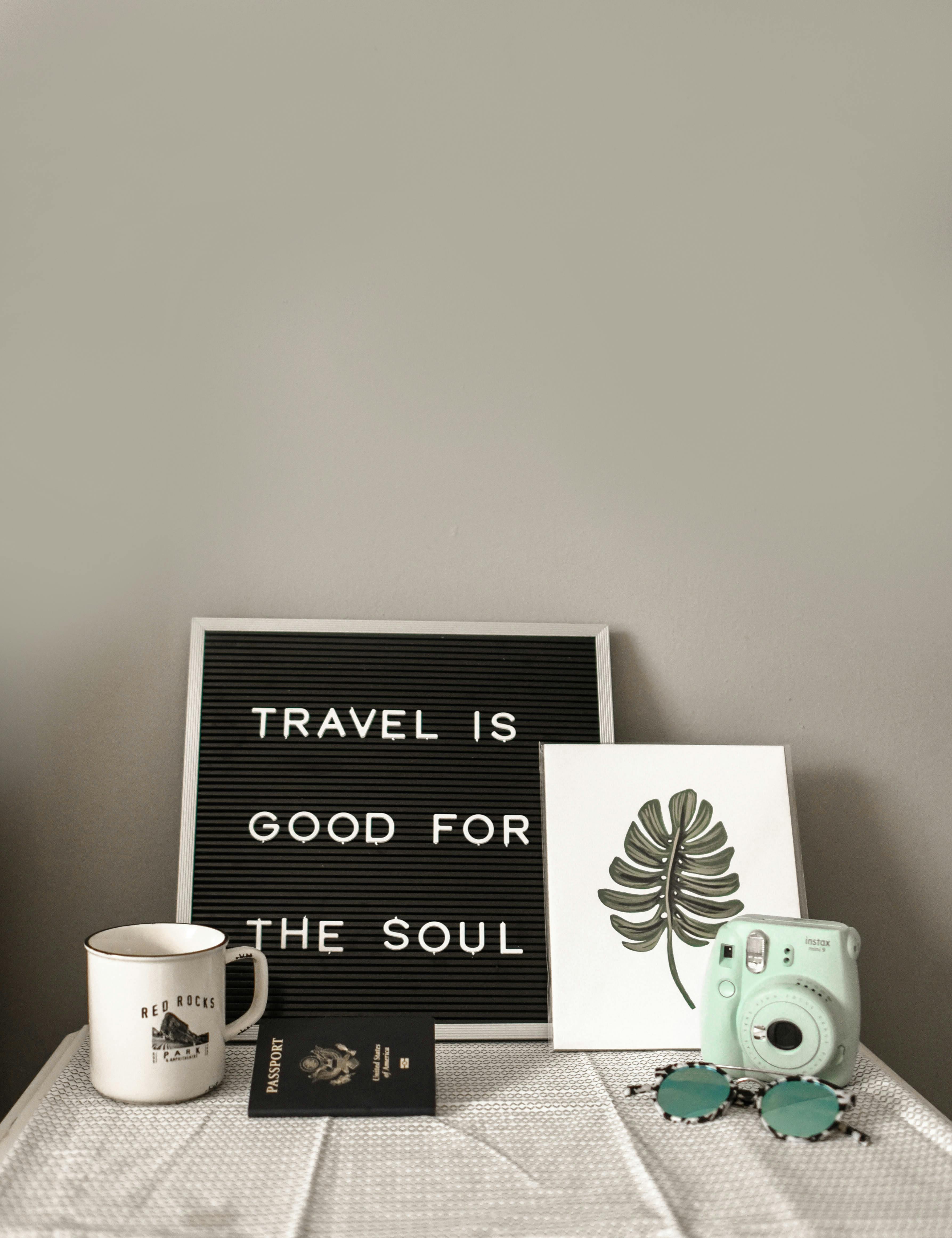 Flat-lay of passport, instant camera, mug and sunglasses