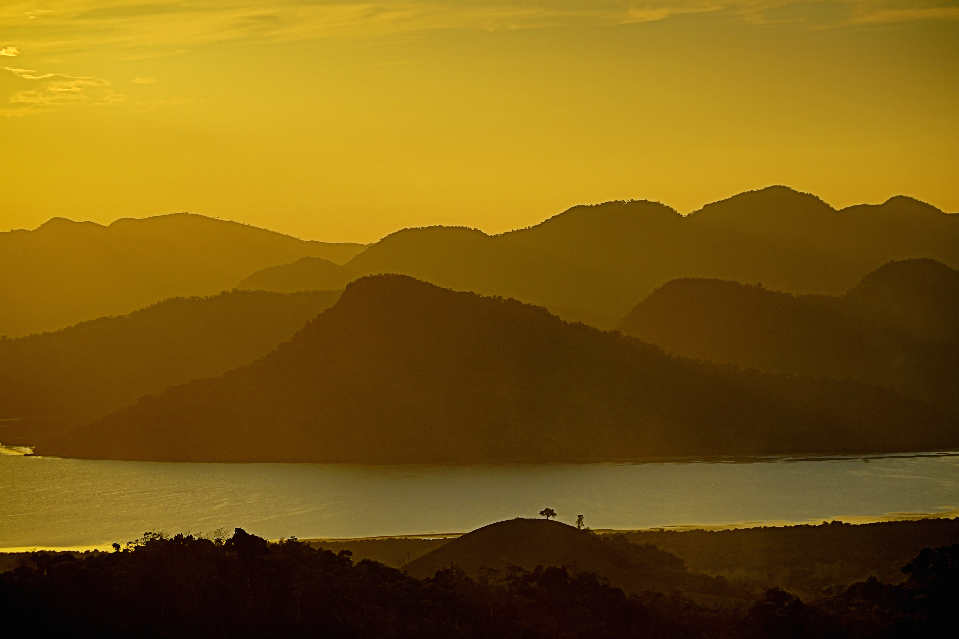 Coron Bay at golden hour with karst islands silhouetted against warm sky, Palawan, Philippines