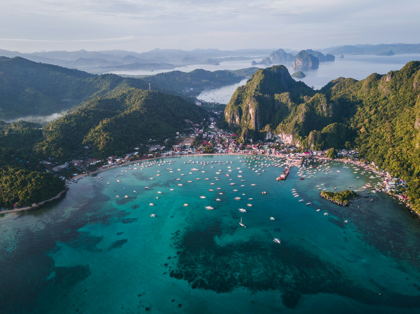 Bangka boats moored beneath El Nido limestone cliffs