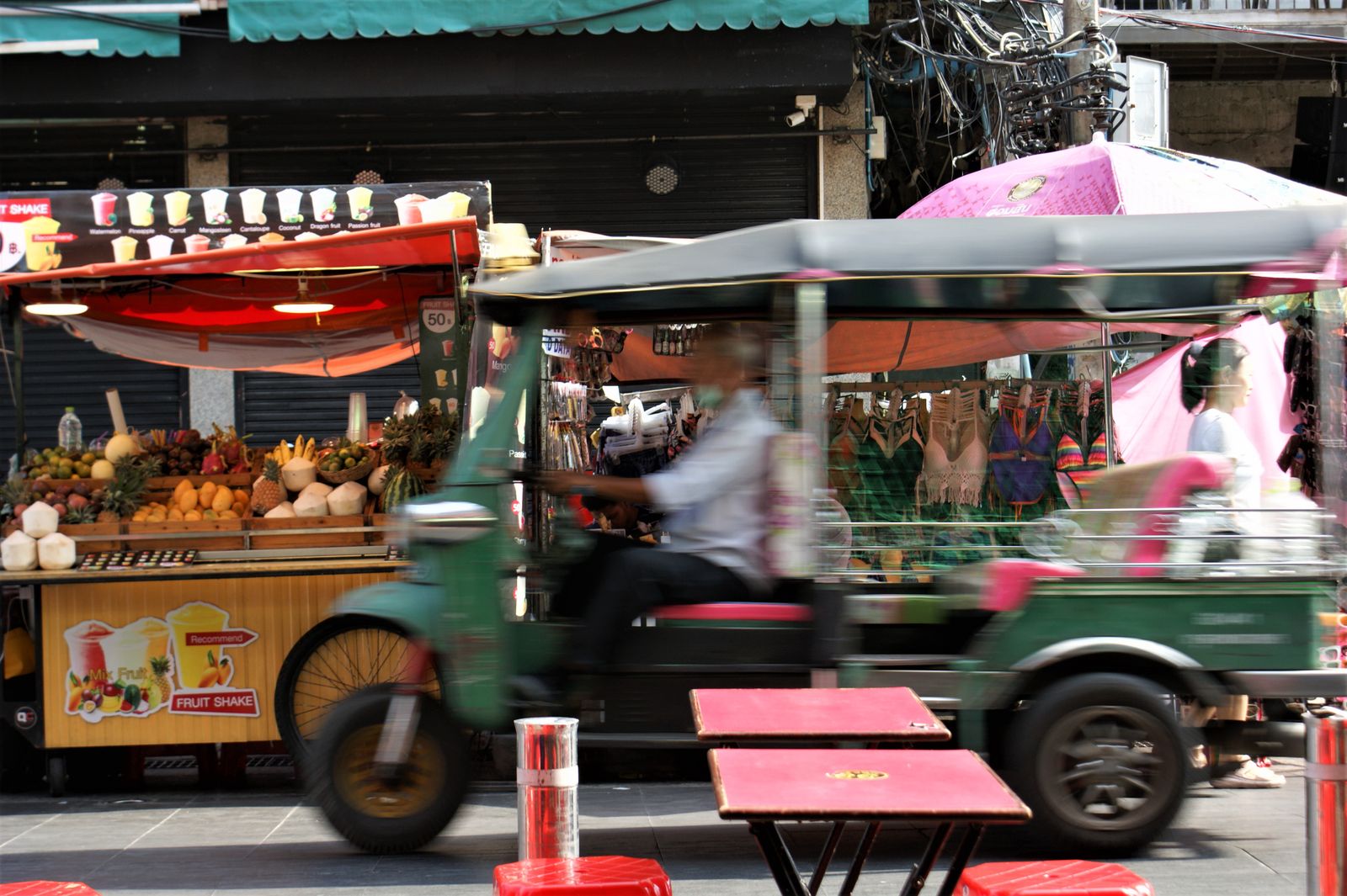 Tuk-tuk speeding past Bangkok market stalls