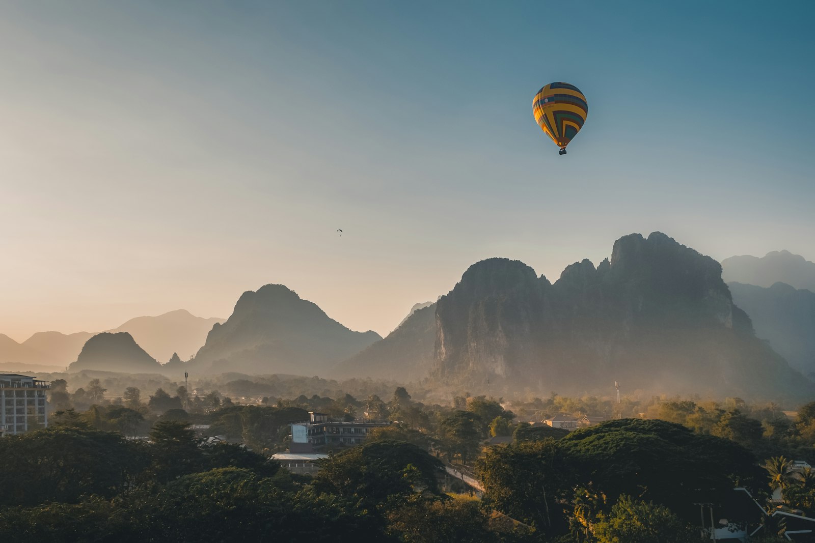 Hot air balloon drifting over karst limestone mountains at sunset in Vang Vieng, Laos