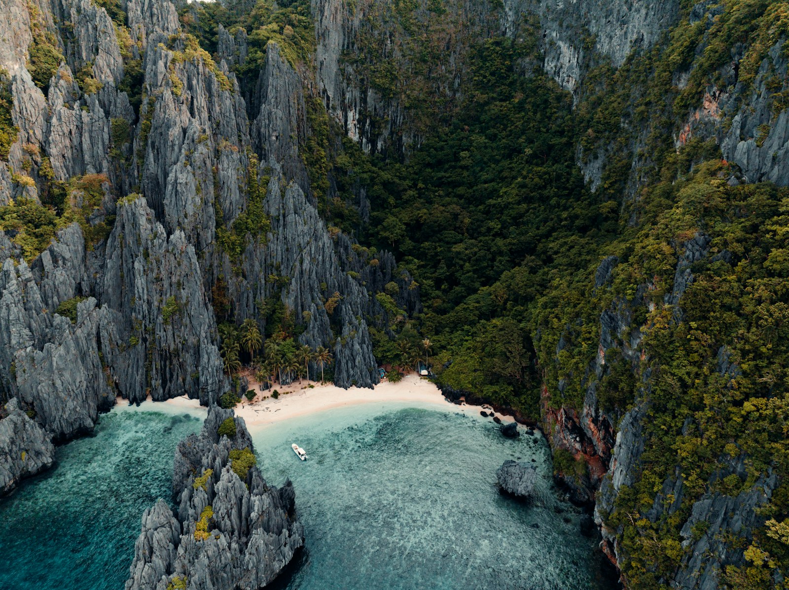 Aerial view of a tropical island cove with limestone cliffs and turquoise water, Palawan-style scenery