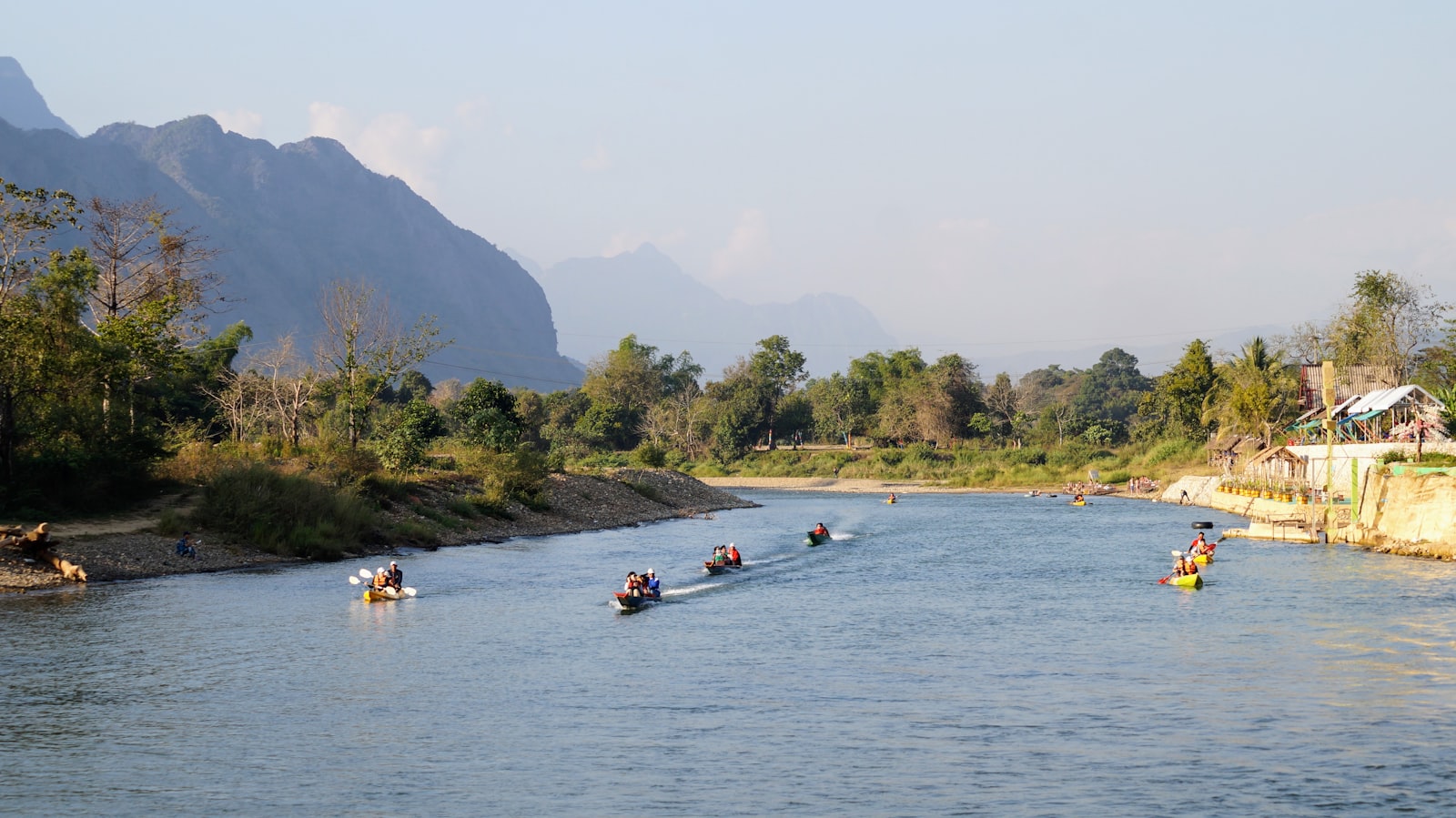 Long wooden passenger boat on the Mekong River in Laos, viewed from a similar boat