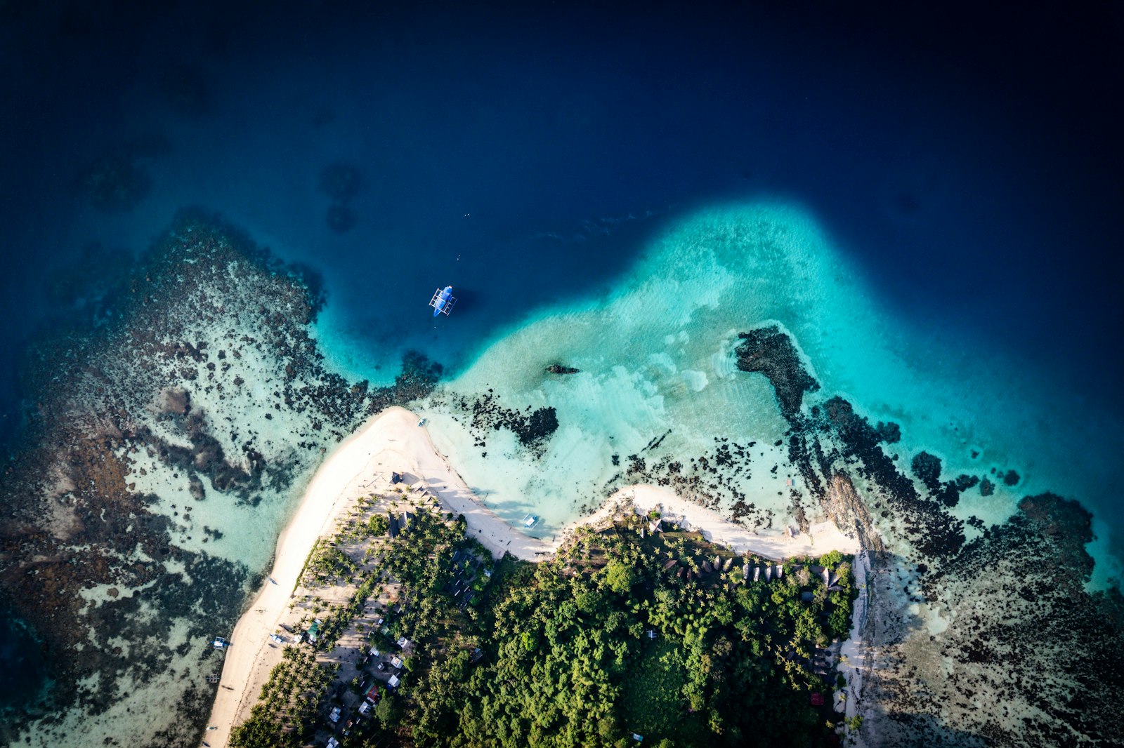 Aerial view of a tropical island coastline with clear blue water and a sandy beach
