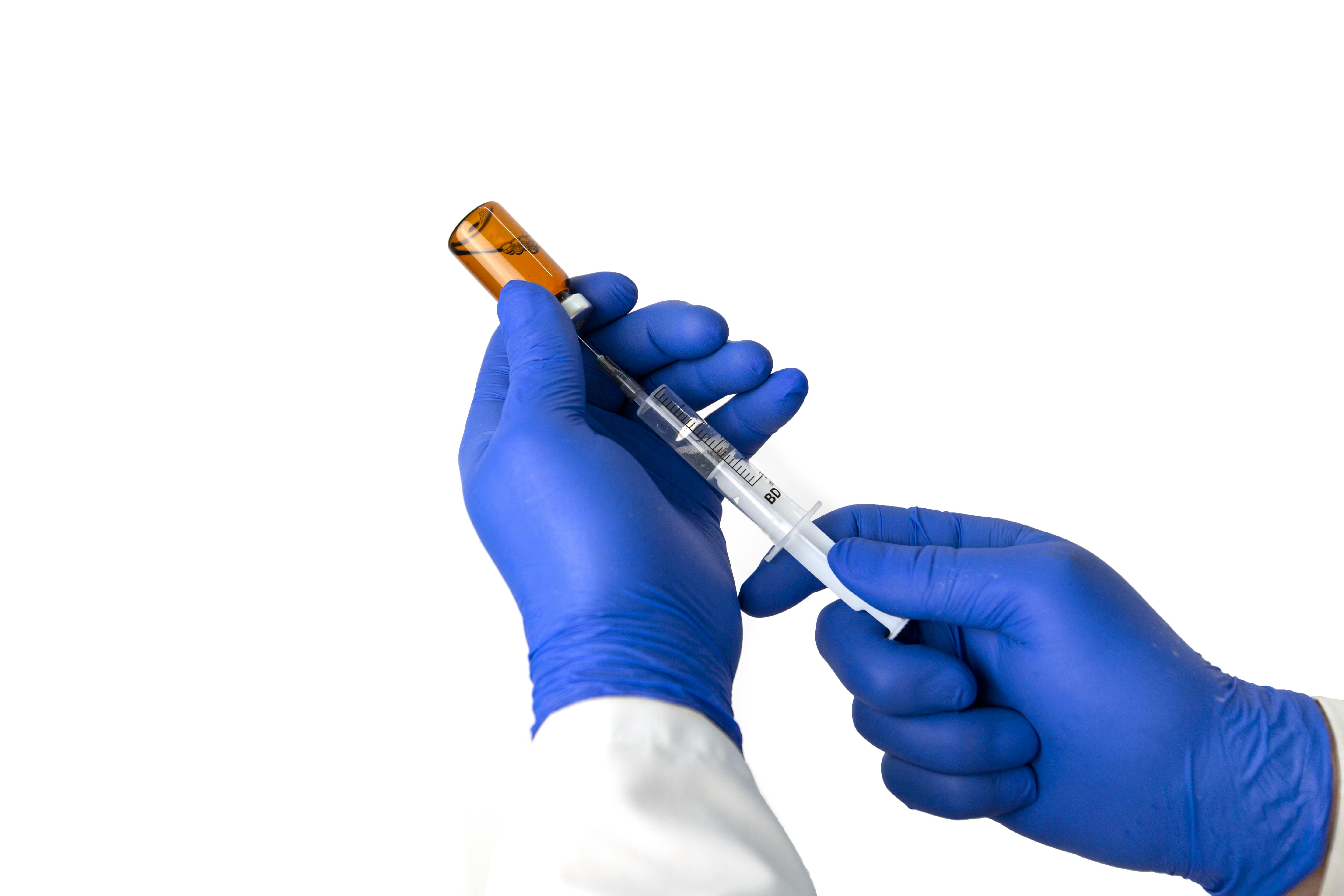 Gloved hands preparing a vaccine syringe
