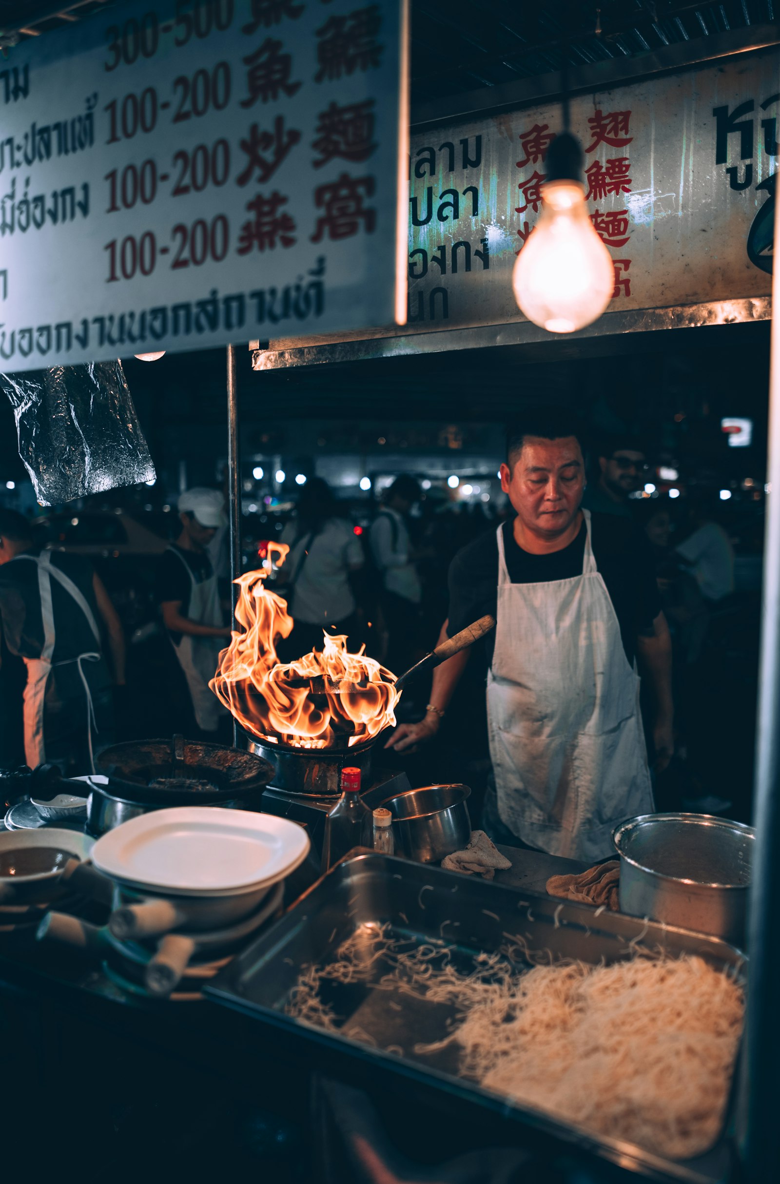 Thai street food vendor cooking at a hawker stall — busy stall, high turnover, fresh food