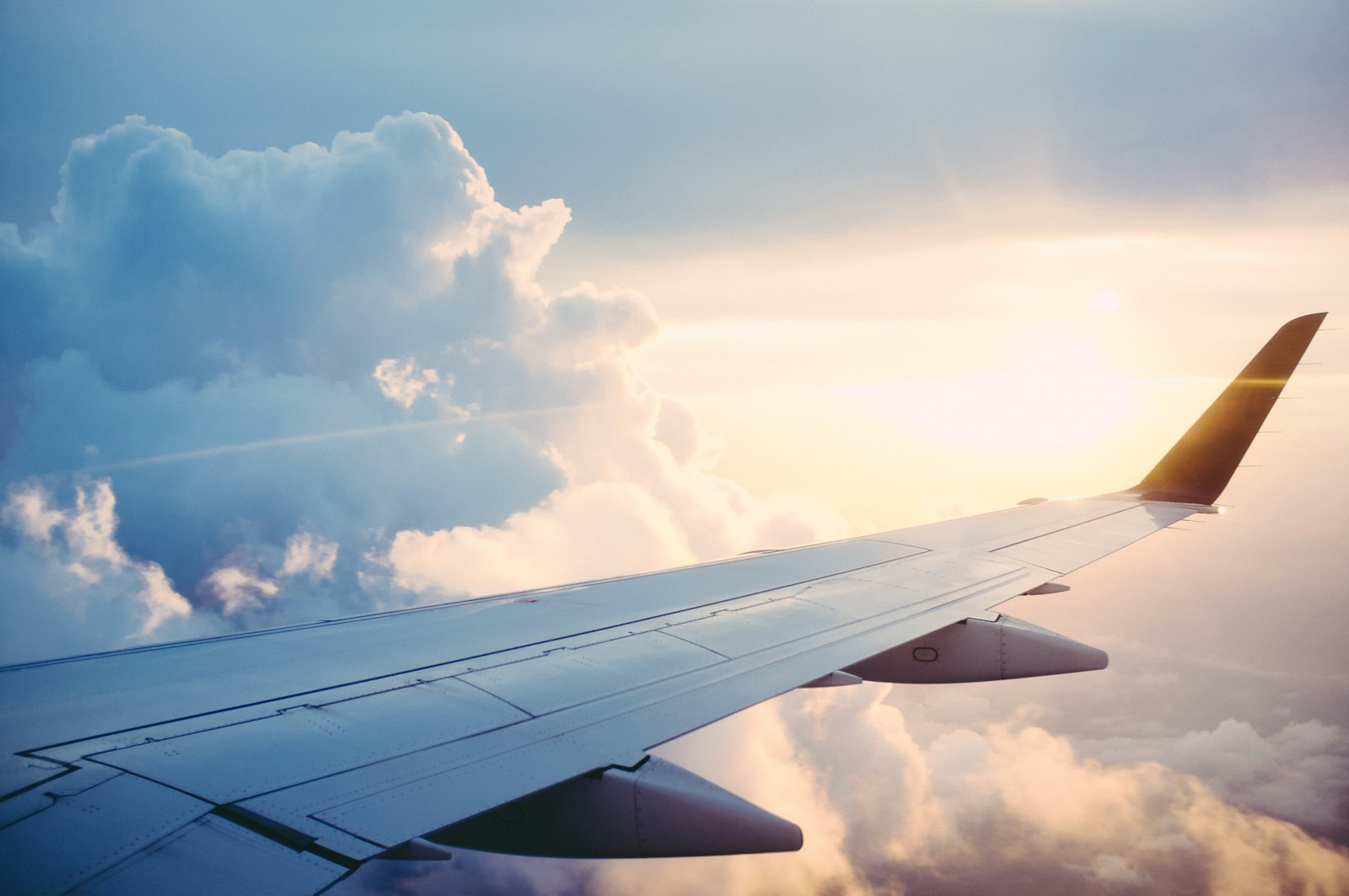 Aircraft wing above clouds in golden sunset light
