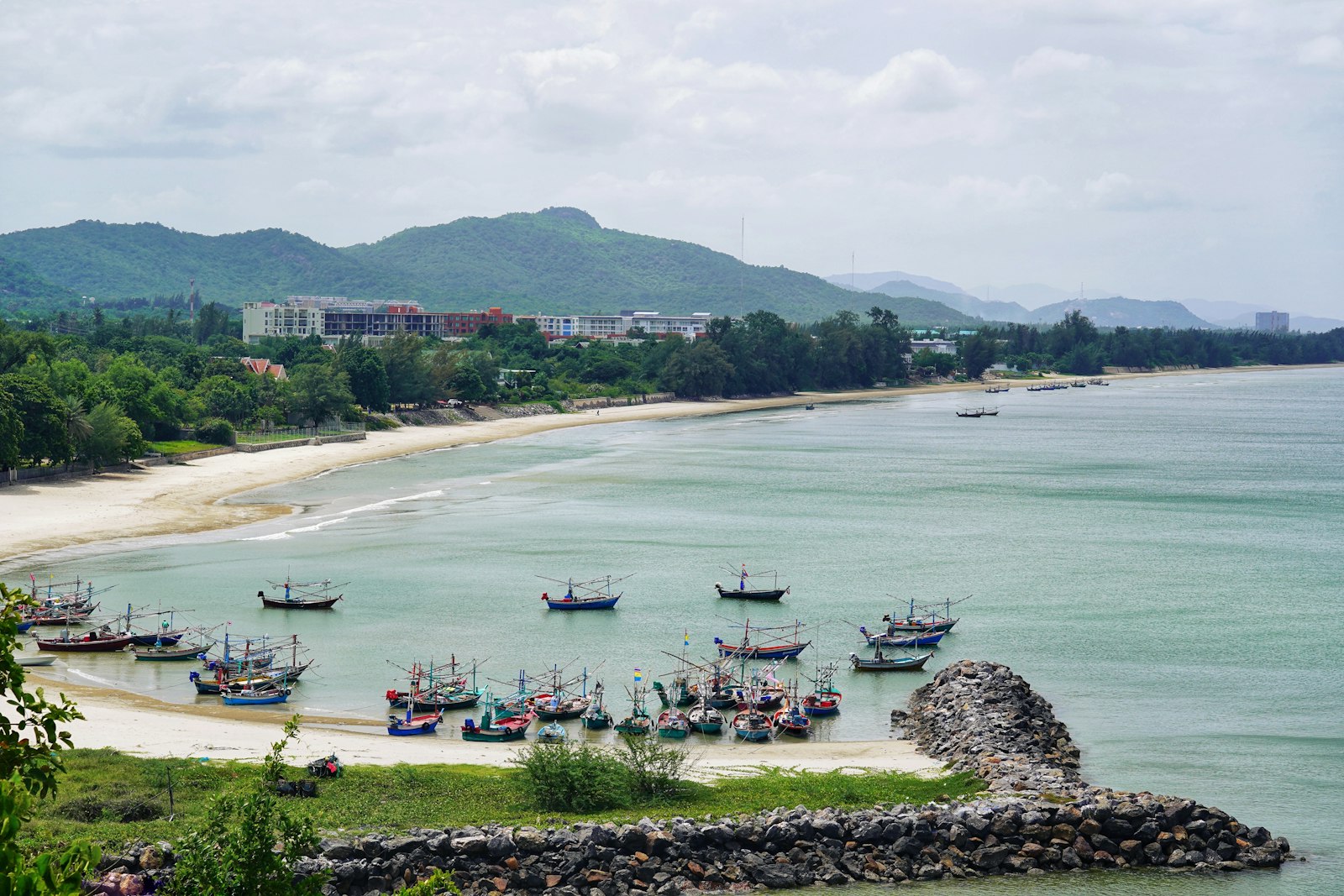 Khao Tao beach near Hua Hin, Thailand — wooden fishing boats moored in a calm bay backed by green hills