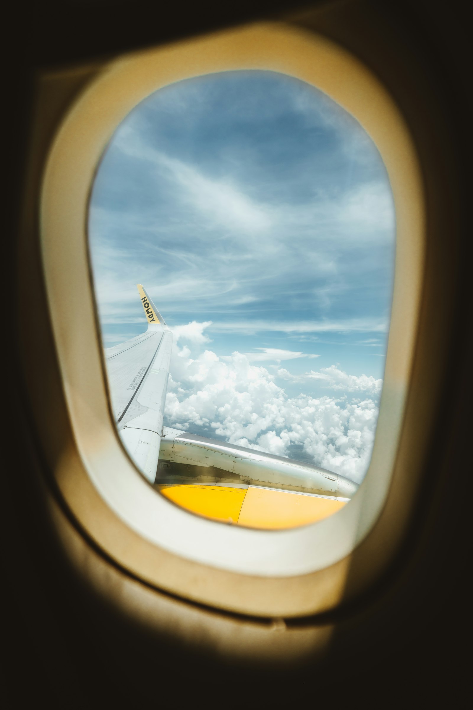 View of clouds and an airplane wing through a cabin window