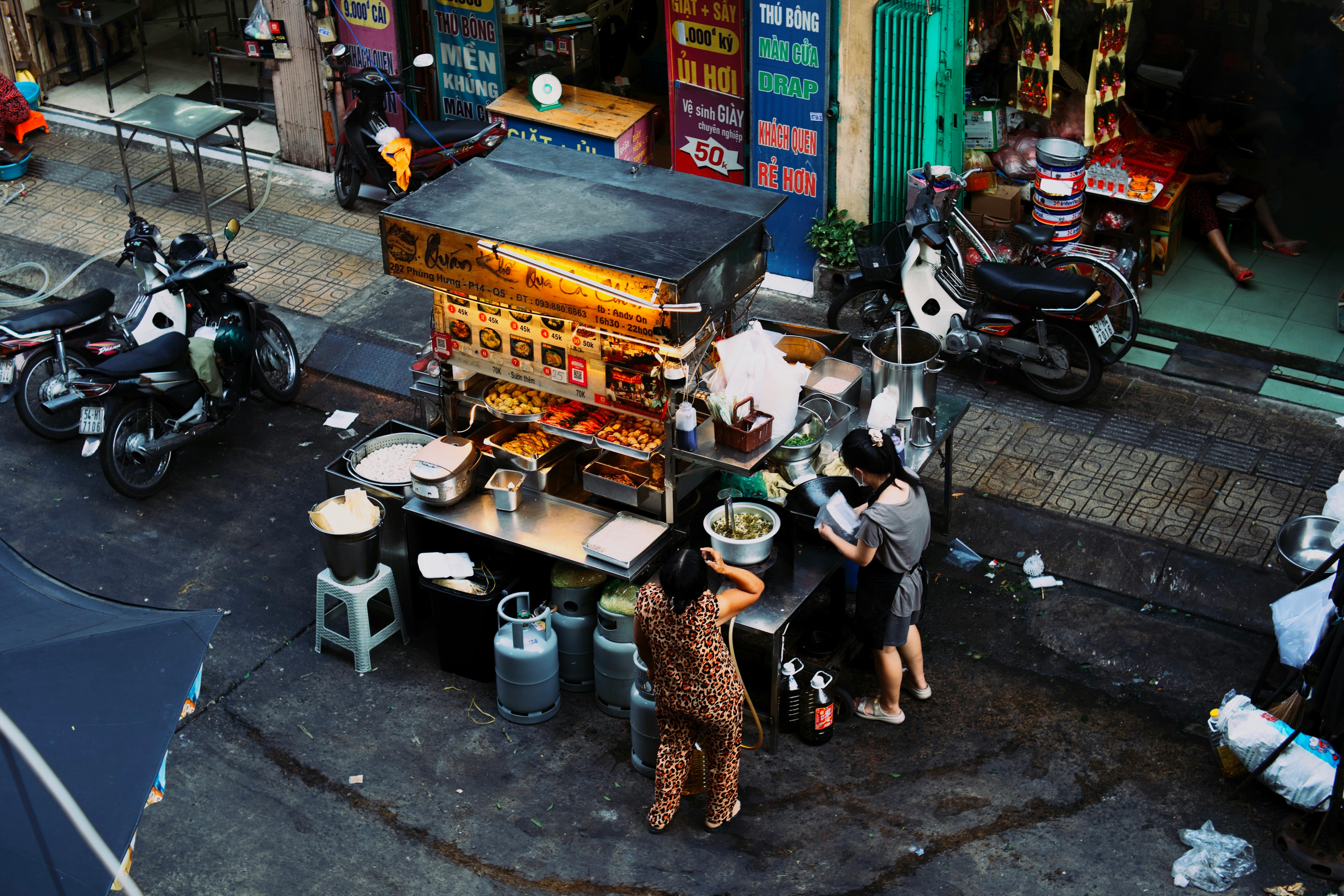 Two women preparing food at a Vietnamese street stall