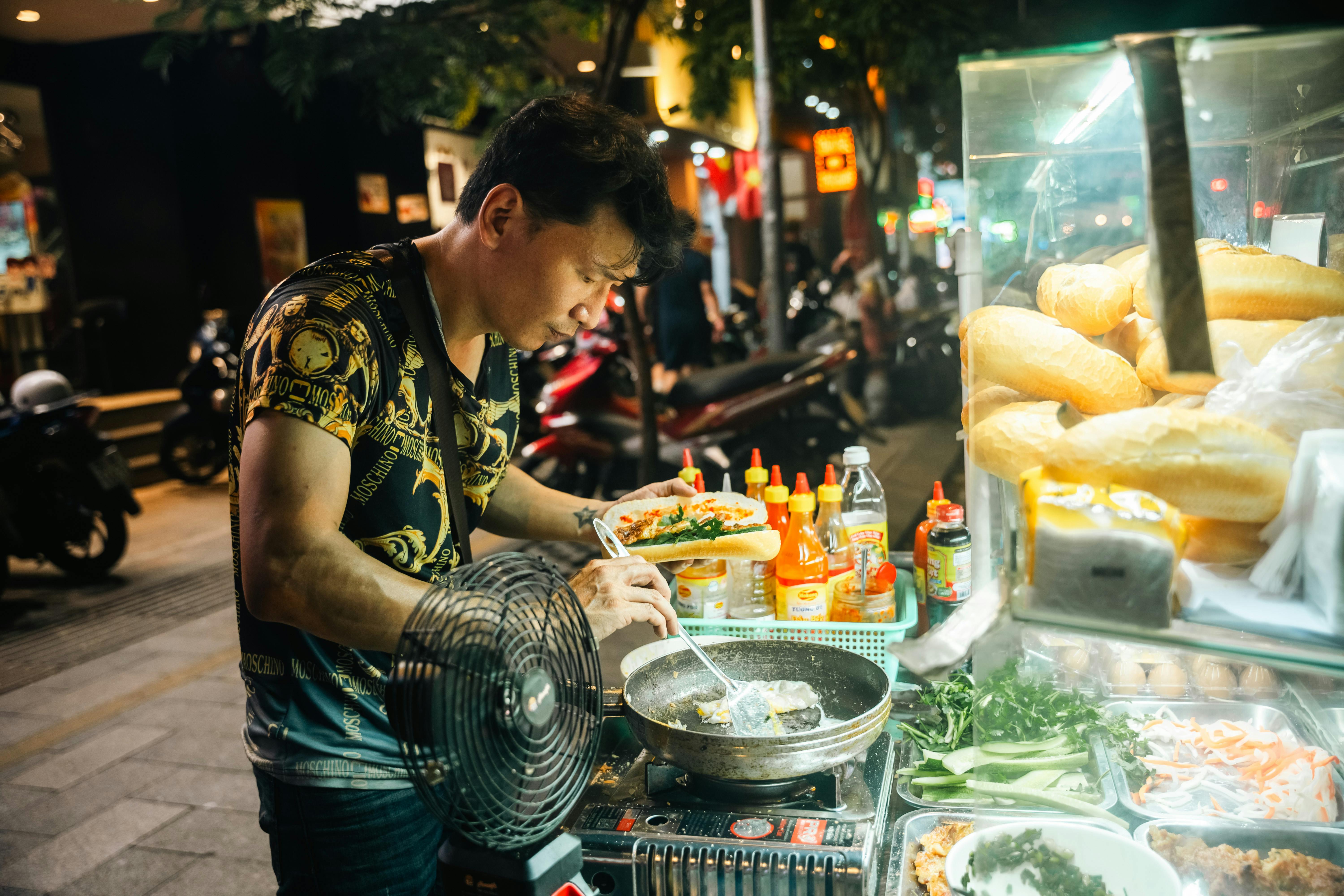 Vendor assembling banh mi at a night market