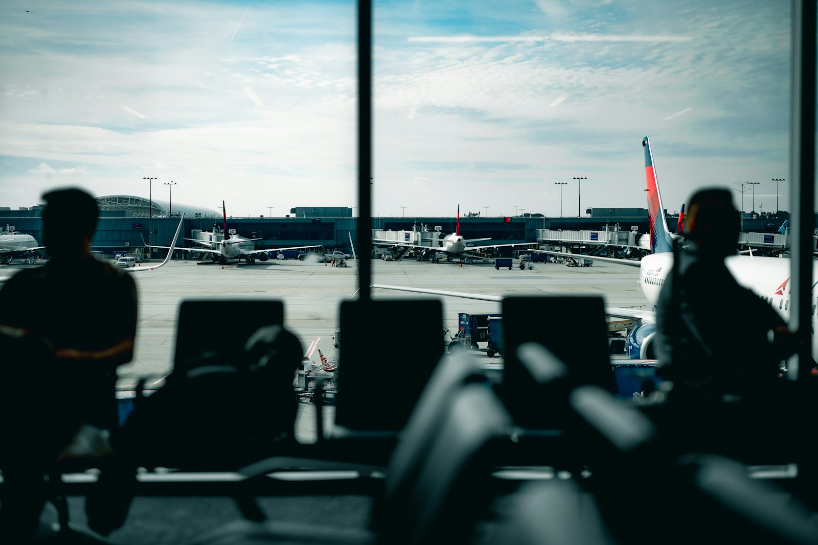 Passengers waiting at an airport gate with planes outside