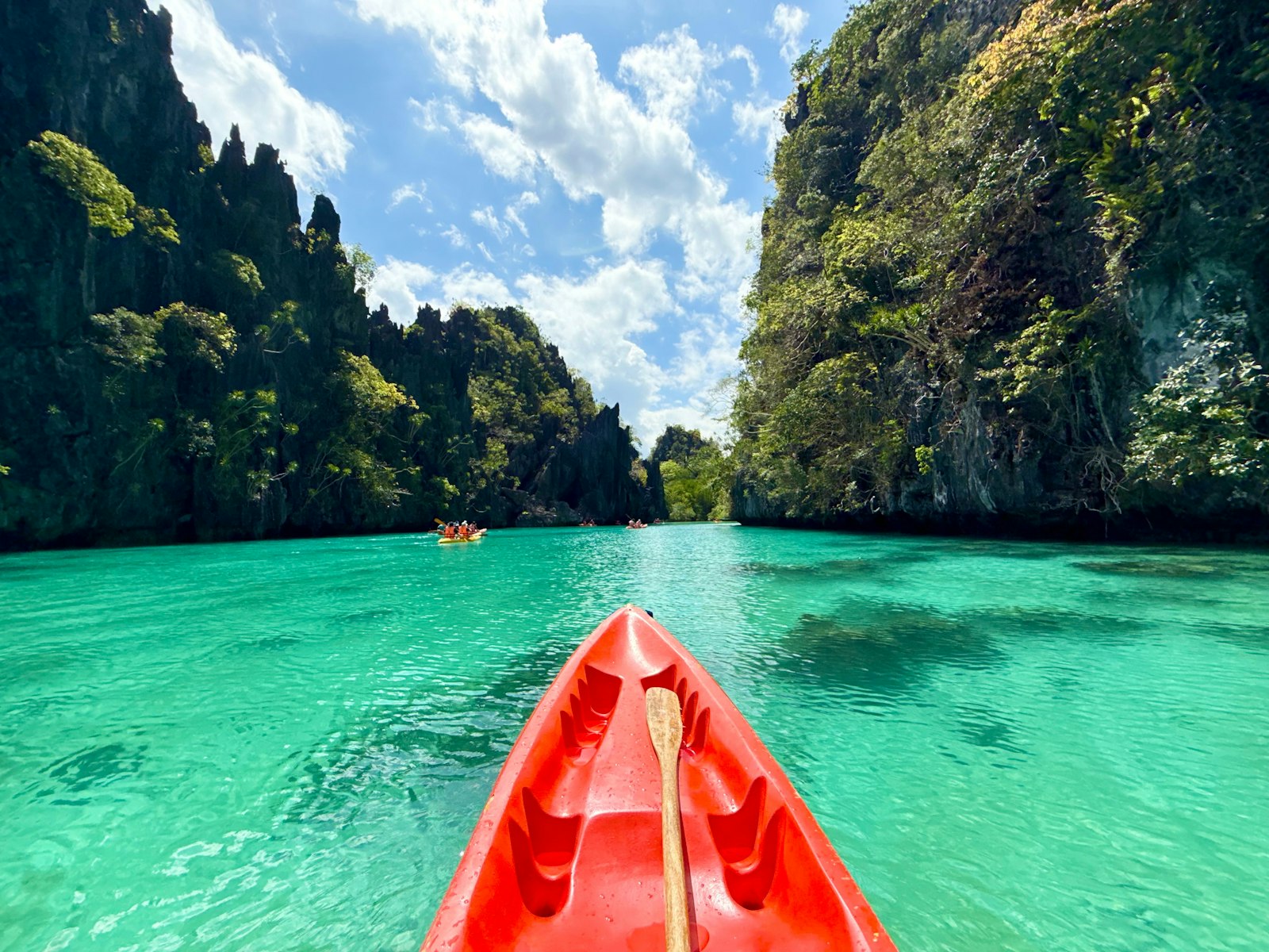 Kayaking through turquoise water surrounded by limestone karst cliffs in El Nido, Palawan
