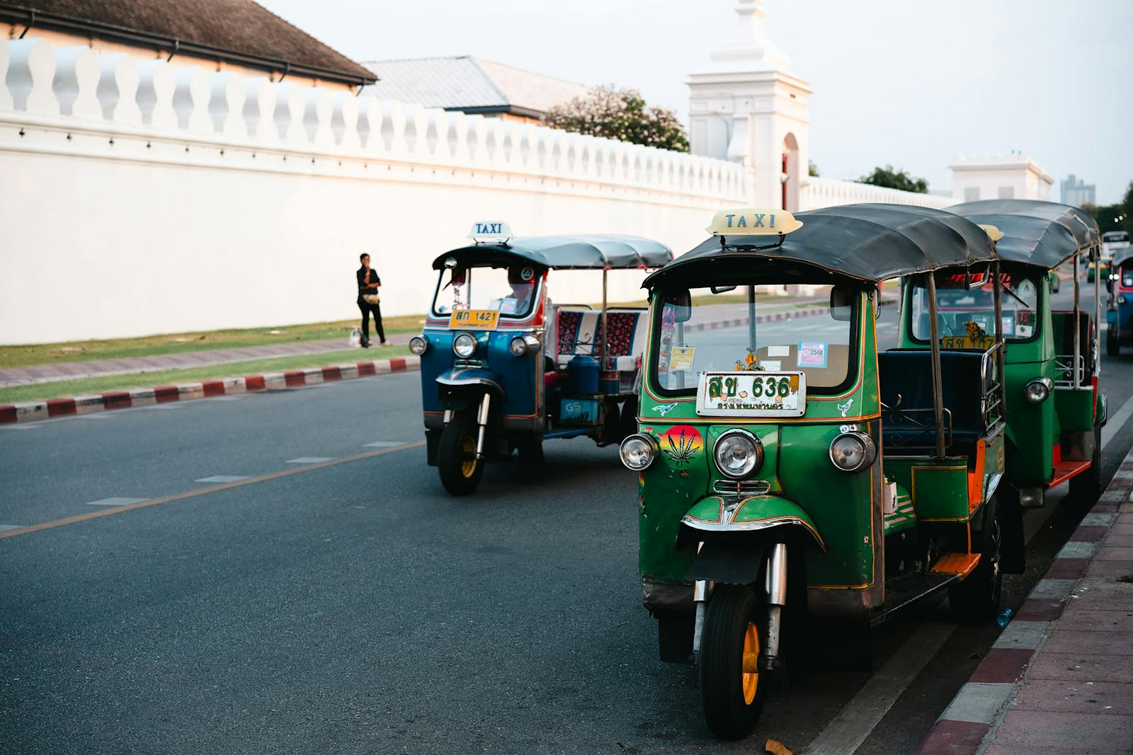 Green and blue tuk-tuks parked on a Bangkok street
