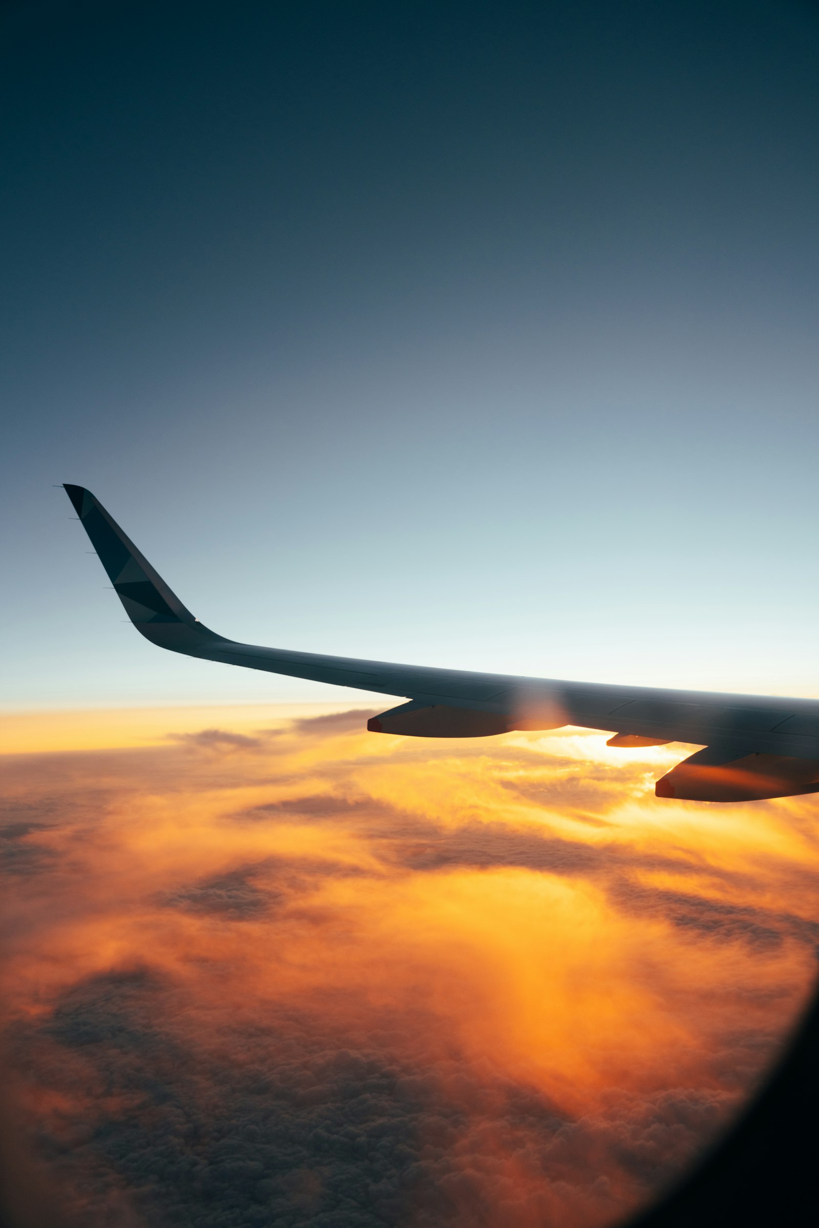 Airplane wing above clouds at sunrise